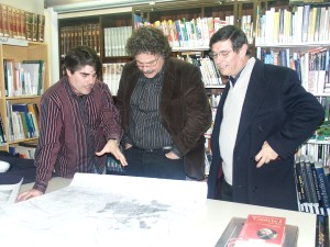 Joan Tard, al centre de la imatge, escoltant les explicacions de Llus Oliveras i Valent Carrera a la Biblioteca Municipal. / JORDI LARGO